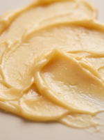 A close-up shot of the creamy spread of Formed Relief Balm swirled on a light beige surface.
